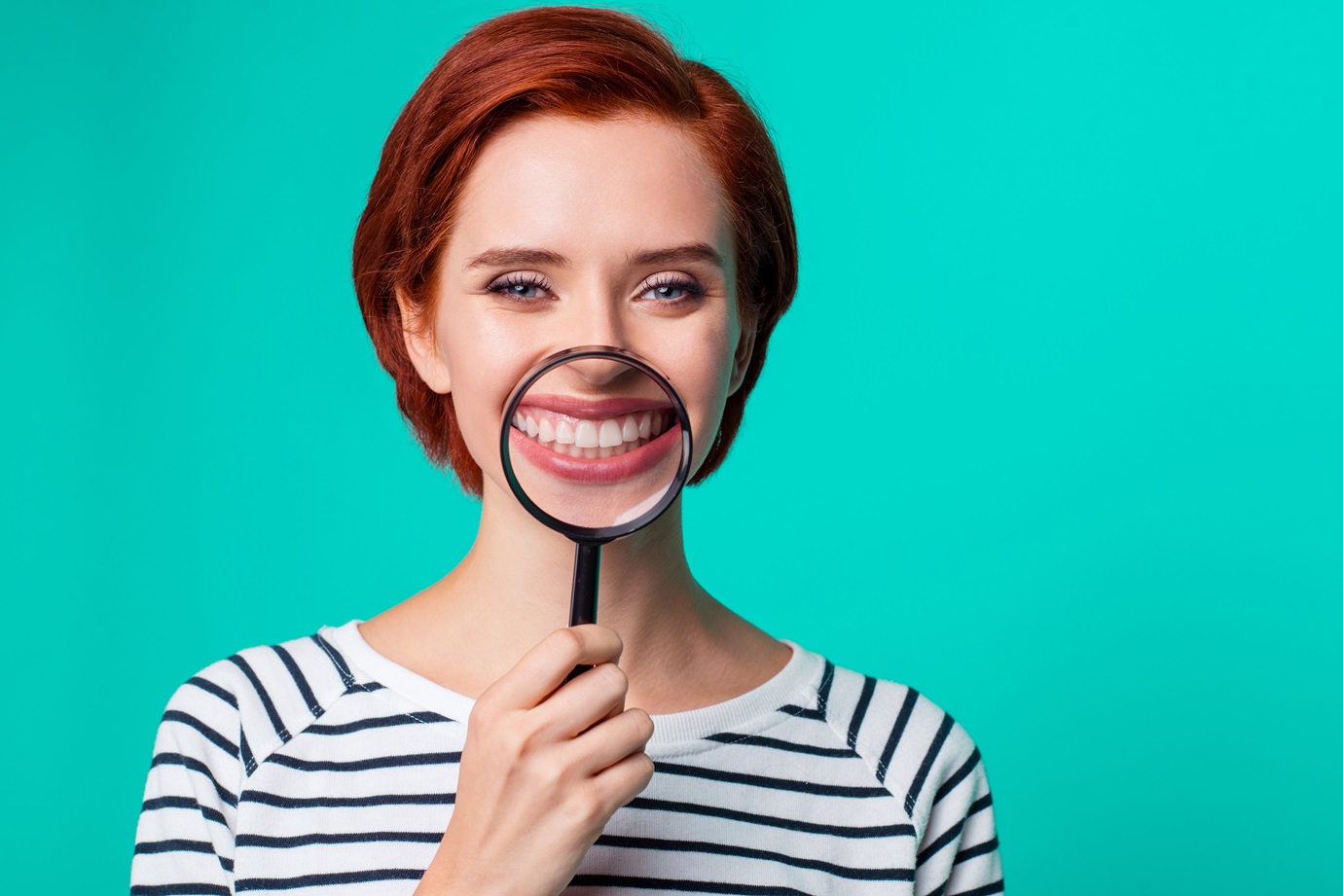 Closeup studio photo portrait of charming satisfied cute friendly caucasian teen girl holding transparent magnifier make wide hollywood smile wearing black pullover isolated bright background