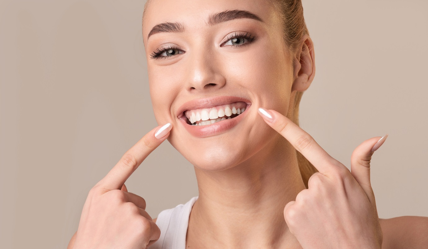 Young Woman Touching Mouth Smiling To Camera On Beige Background