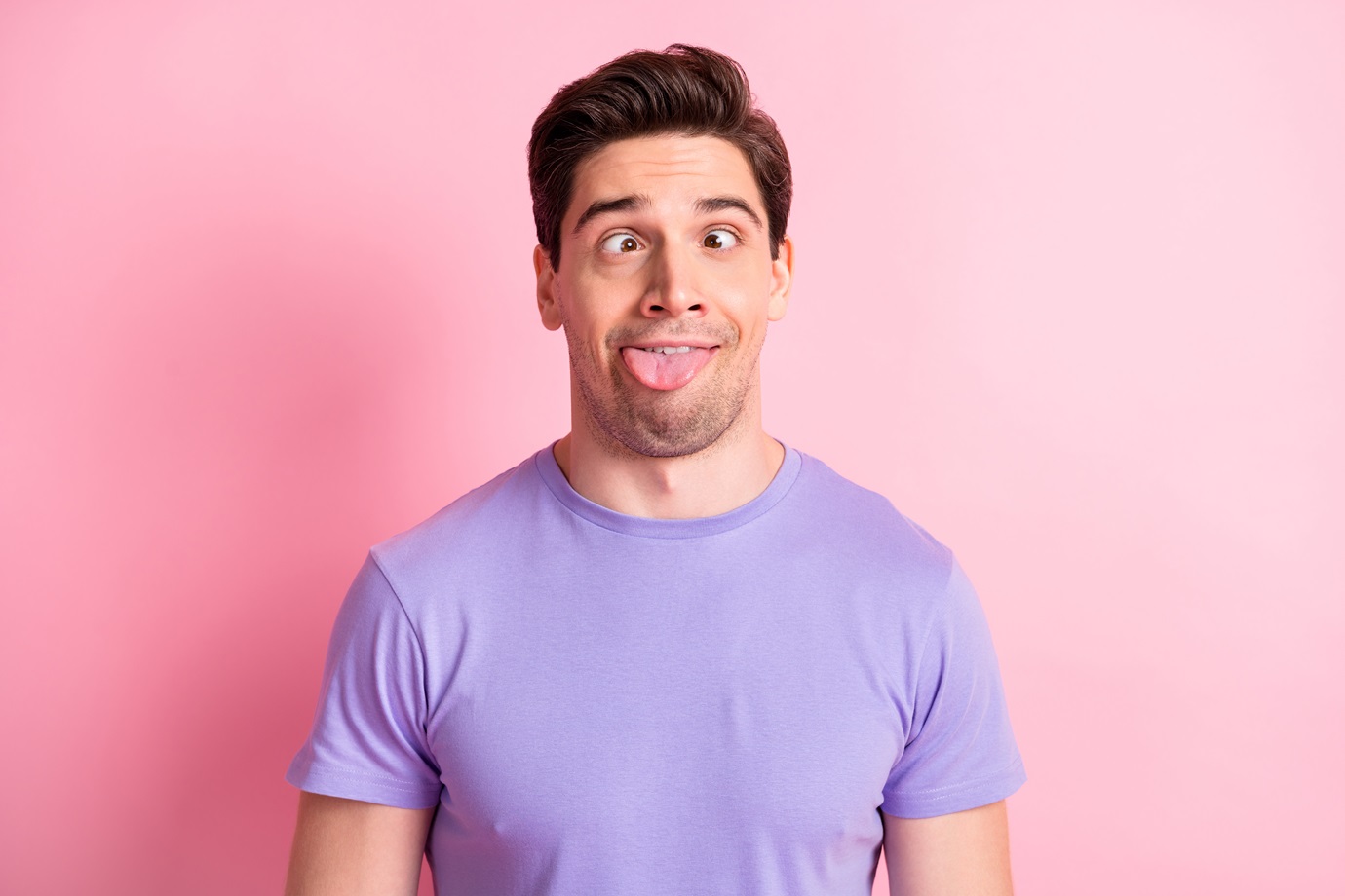 Portrait of attractive cheerful crazy fool guy grimacing teasing having fun isolated over pink pastel color background