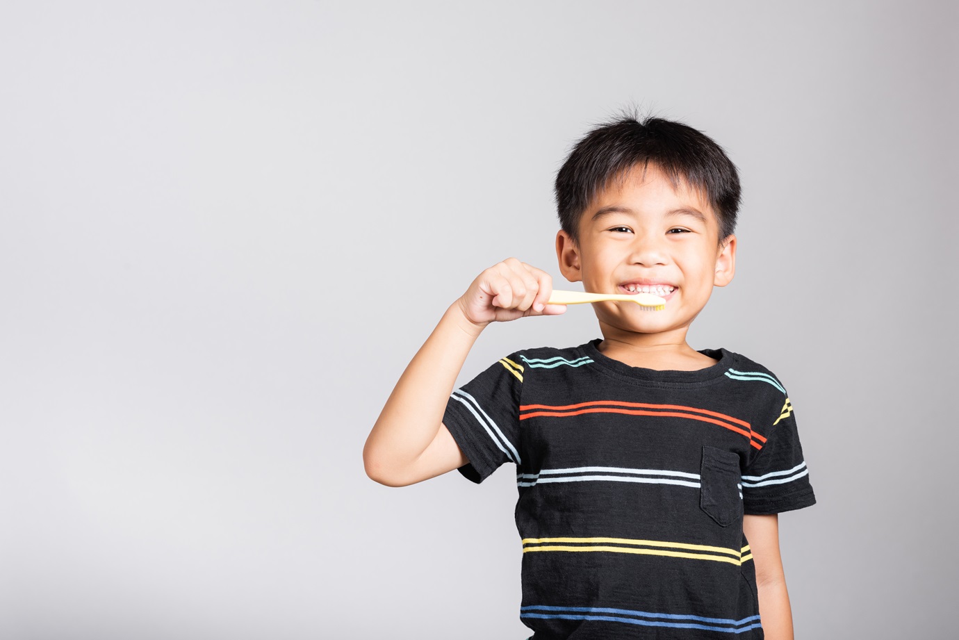 Little cute kid boy 5-6 years old brushing teeth and smile in studio shot isolated