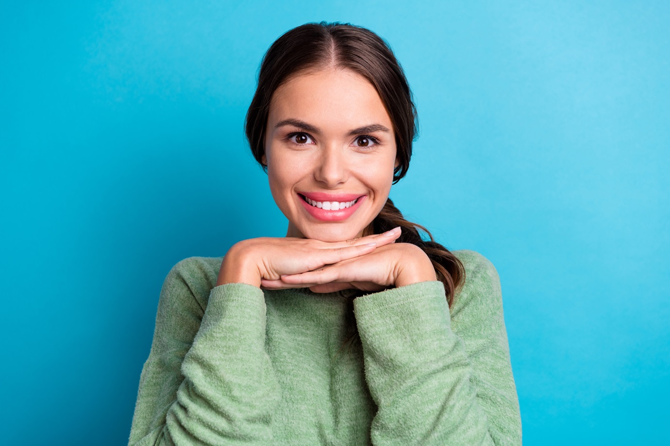 Photo of pretty positive person hands under chin beaming smile isolated on blue color background